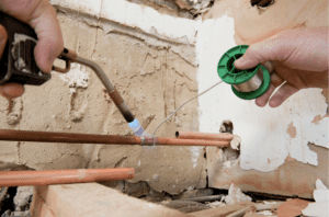 plumber checks for green corrosion on pipes