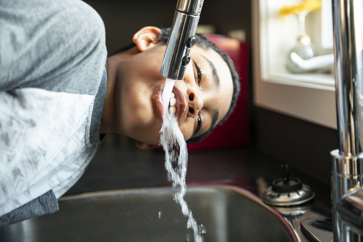 child drinking water from the sink